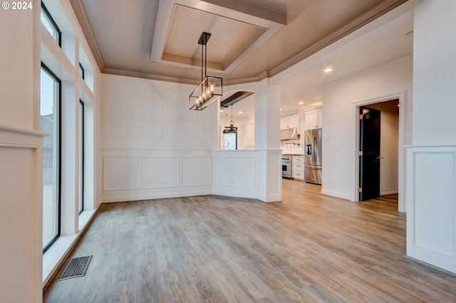 unfurnished dining area with a raised ceiling, light wood-type flooring, and crown molding