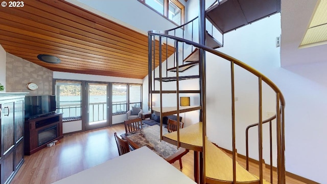 staircase featuring high vaulted ceiling, wood ceiling, and wood finished floors