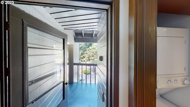 doorway to outside featuring stacked washer / dryer