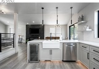 kitchen with dishwasher, sink, wine cooler, decorative light fixtures, and kitchen peninsula