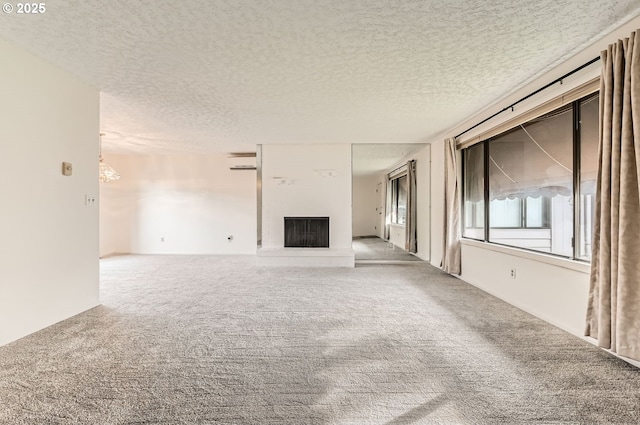 unfurnished living room with a textured ceiling, carpet, and a notable chandelier