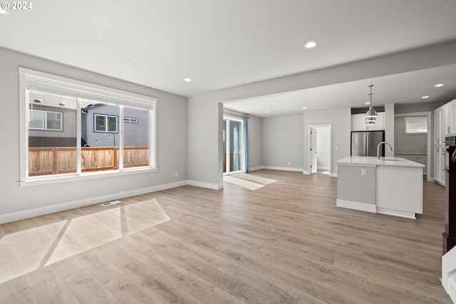 unfurnished living room featuring sink and light hardwood / wood-style flooring