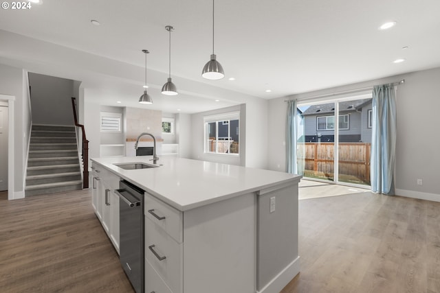 kitchen with a kitchen island with sink, sink, white cabinetry, light hardwood / wood-style flooring, and stainless steel dishwasher