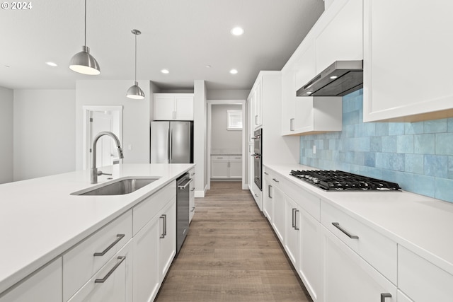 kitchen with white cabinetry, pendant lighting, stainless steel appliances, light wood-type flooring, and sink