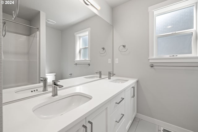 bathroom with walk in shower, vanity, tile patterned flooring, and toilet