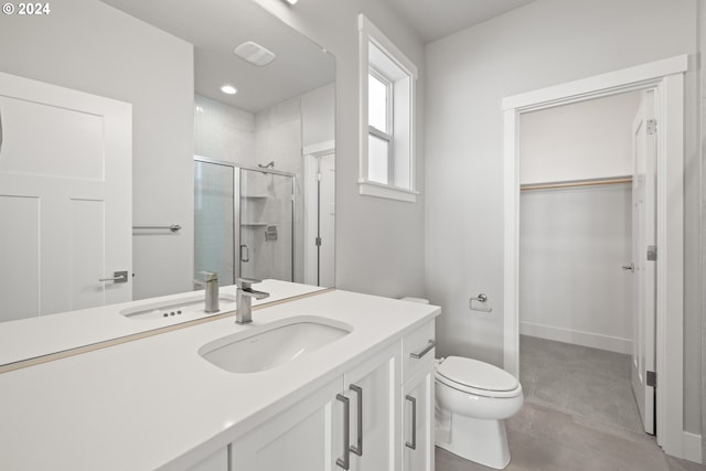 bathroom with vanity, toilet, and a shower with door