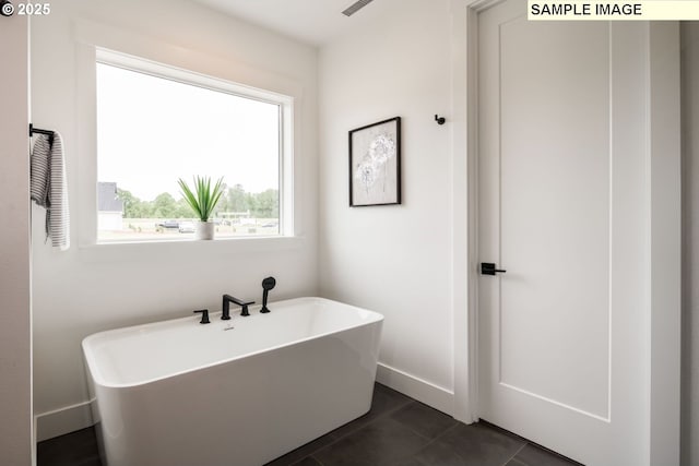 full bathroom featuring tile patterned flooring, a freestanding tub, and baseboards