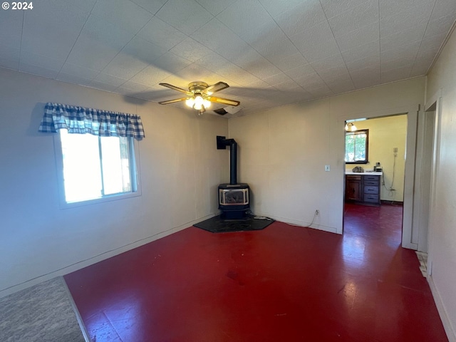 empty room with a wood stove and ceiling fan