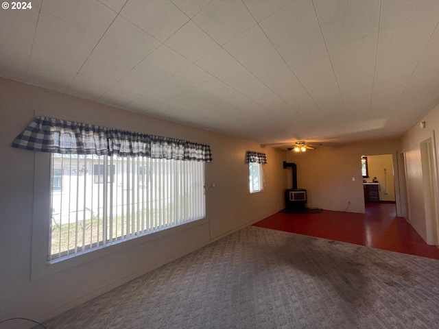 unfurnished room with a wood stove and ceiling fan