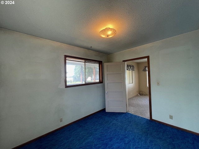 unfurnished bedroom with dark carpet and a textured ceiling