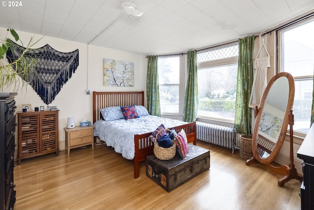 bedroom with light wood-type flooring, a wall of windows, and radiator