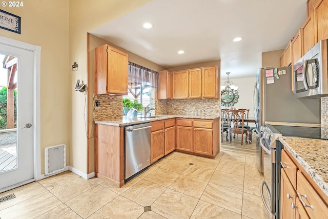 kitchen with backsplash, light stone countertops, light tile patterned floors, sink, and stainless steel appliances