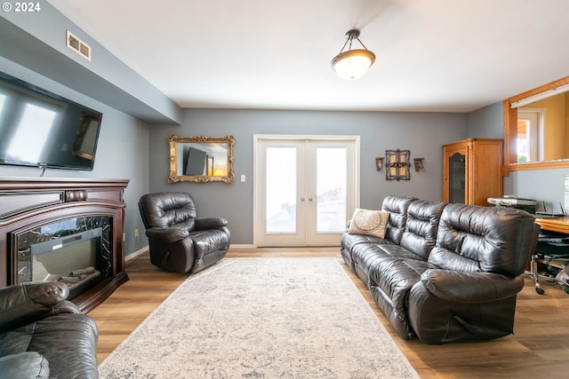 living room with light wood-type flooring, french doors, and a healthy amount of sunlight