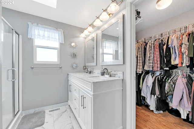 bathroom with a shower with shower door, tile patterned floors, and vanity