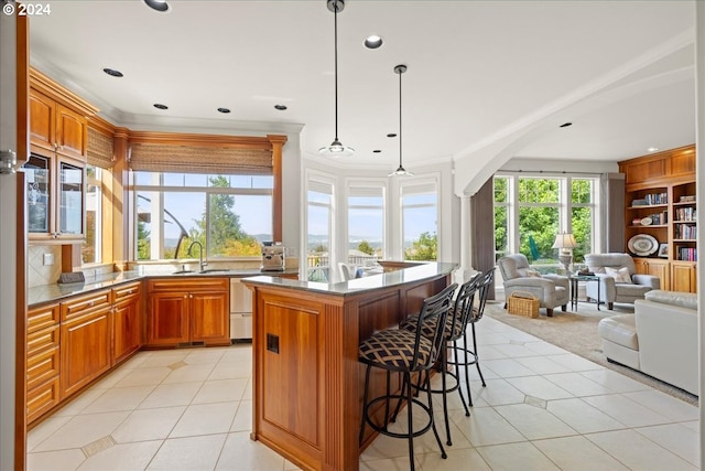 kitchen featuring pendant lighting, light tile patterned floors, sink, a kitchen island, and a breakfast bar area