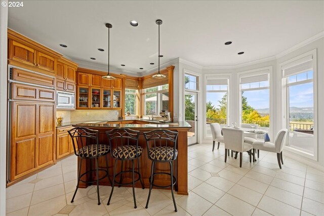 kitchen featuring ornamental molding, decorative light fixtures, white microwave, and a wealth of natural light