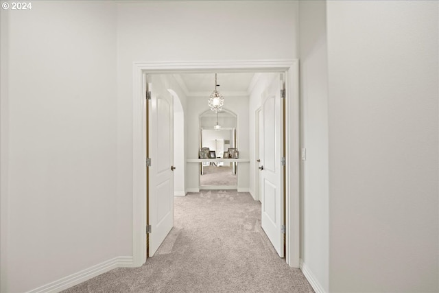 hallway featuring ornamental molding and light colored carpet