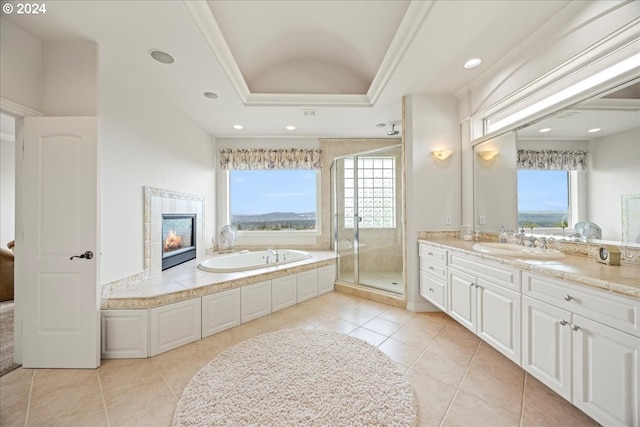 bathroom with shower with separate bathtub, tile patterned flooring, a tiled fireplace, a raised ceiling, and vanity