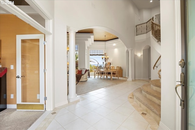 foyer entrance with a towering ceiling, decorative columns, and light colored carpet