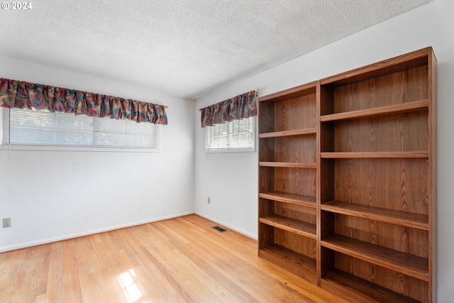 empty room with light hardwood / wood-style floors and a textured ceiling