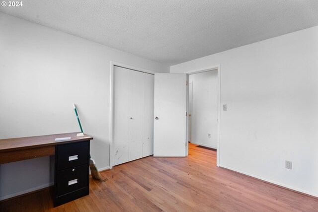 bedroom featuring a closet, a textured ceiling, and light hardwood / wood-style flooring