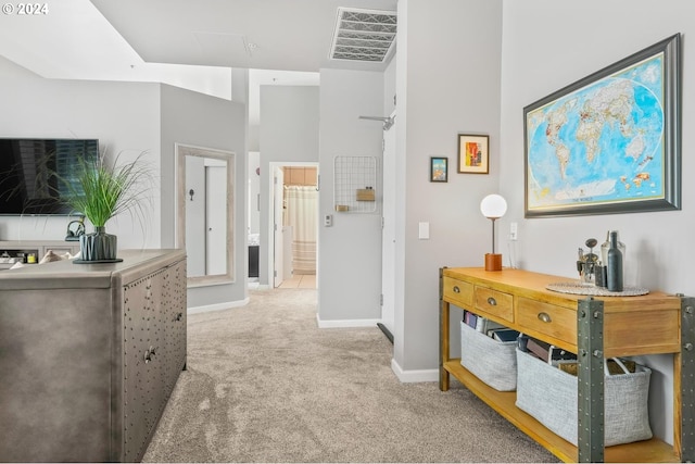 hall with light colored carpet and a high ceiling