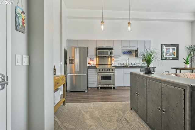 kitchen featuring tasteful backsplash, pendant lighting, sink, appliances with stainless steel finishes, and dark carpet