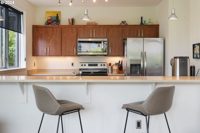 kitchen featuring hanging light fixtures, stainless steel appliances, and a breakfast bar area