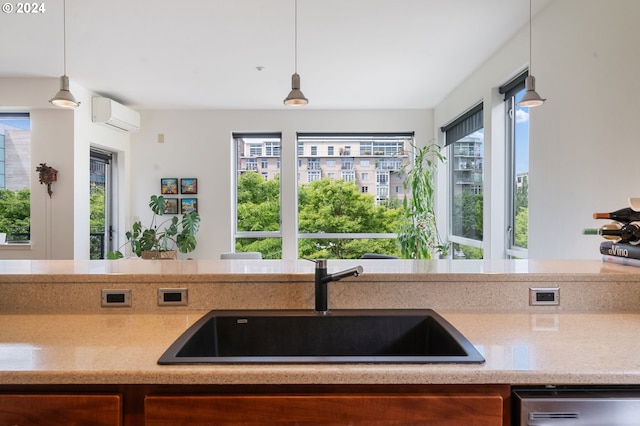 kitchen featuring decorative light fixtures, an AC wall unit, stainless steel dishwasher, and sink