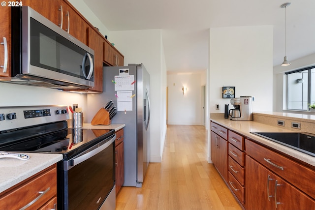 kitchen featuring light hardwood / wood-style flooring, stainless steel appliances, decorative light fixtures, and sink