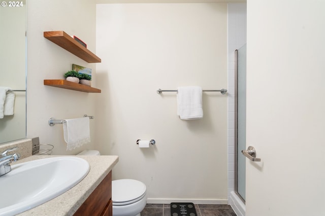 bathroom featuring tile patterned flooring, vanity, an enclosed shower, and toilet