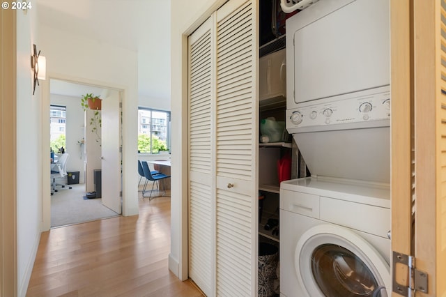 laundry area with light wood-type flooring and stacked washer / dryer