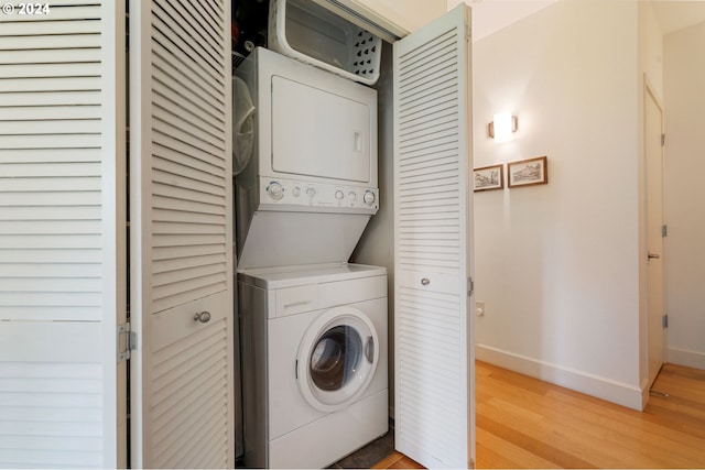 laundry room featuring light wood-type flooring and stacked washer and clothes dryer