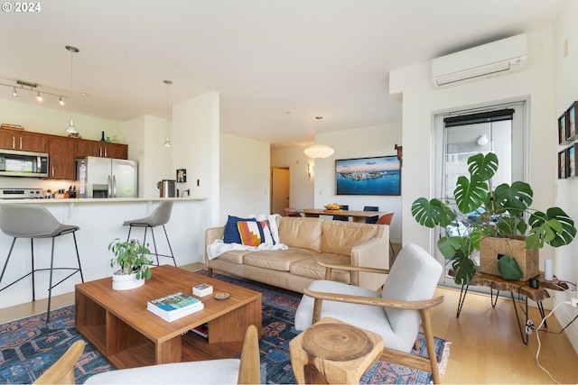 living room with light wood-type flooring and a wall unit AC