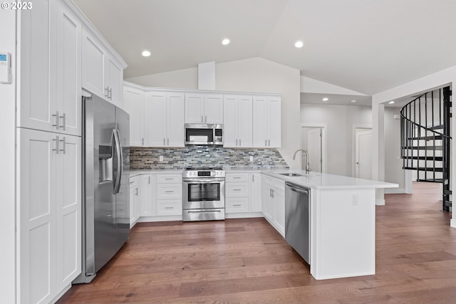 kitchen with appliances with stainless steel finishes, light hardwood / wood-style floors, white cabinets, sink, and vaulted ceiling