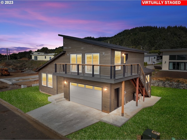 view of front of property with a balcony, a yard, and a garage