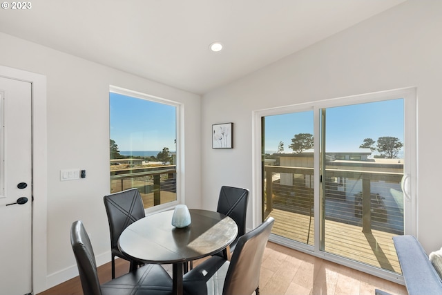 dining space with plenty of natural light, vaulted ceiling, and light hardwood / wood-style floors