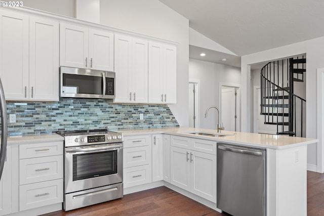 kitchen with lofted ceiling, white cabinetry, appliances with stainless steel finishes, sink, and dark hardwood / wood-style flooring