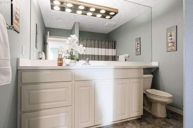 bathroom featuring vanity, a textured ceiling, and toilet