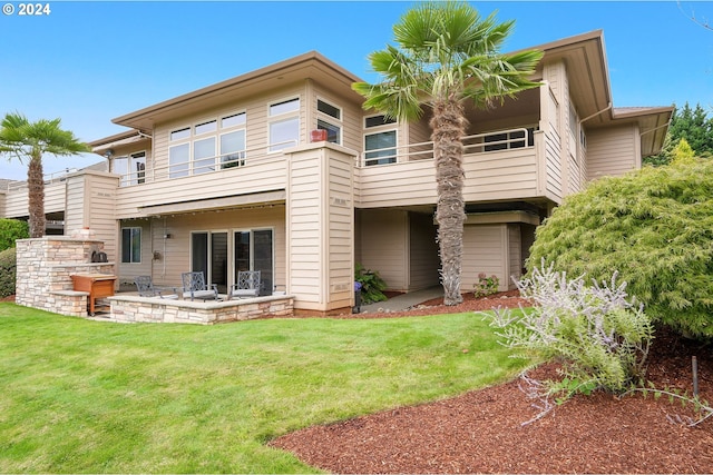 back of property featuring a yard, a balcony, and a patio area