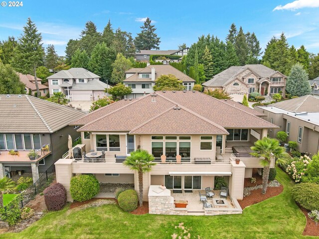 rear view of house with a hot tub, a patio area, and a lawn