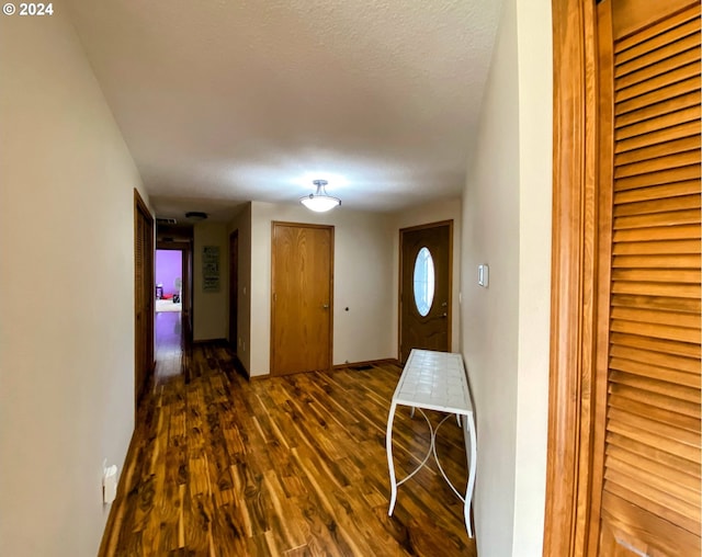 corridor featuring a textured ceiling and dark hardwood / wood-style flooring