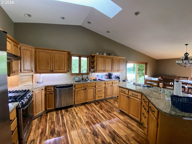 kitchen with dark wood-type flooring, vaulted ceiling with skylight, pendant lighting, a chandelier, and appliances with stainless steel finishes