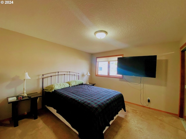 bedroom with a textured ceiling and light colored carpet