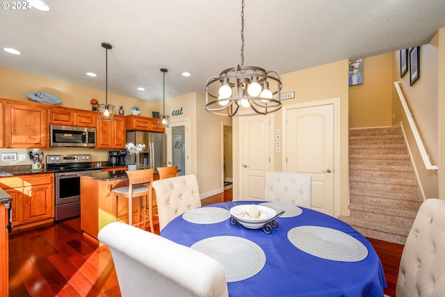 dining space featuring dark wood-type flooring, a textured ceiling, and an inviting chandelier