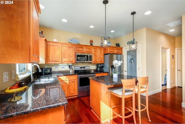 kitchen featuring dark hardwood / wood-style flooring, a kitchen island, sink, pendant lighting, and stainless steel appliances