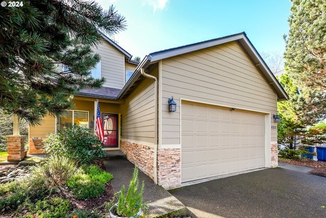4505 NE Tide Ave, Lincoln City, OR 97367 - view of front of property with stone siding, asphalt driveway, and a garage