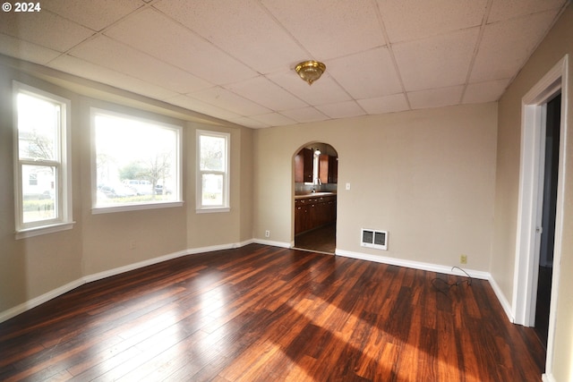 empty room with a paneled ceiling and dark hardwood / wood-style flooring