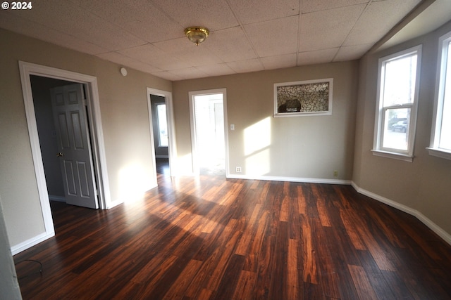 spare room with a drop ceiling and dark wood-type flooring