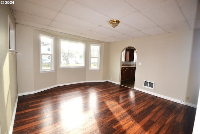 spare room with a drop ceiling and dark hardwood / wood-style flooring